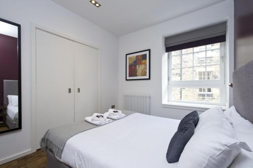 um quarto branco com uma cama e uma janela em Destiny Scotland -The Malt House Apartments em Edimburgo