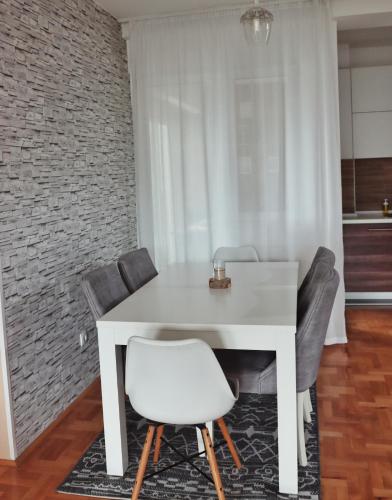 a white table and chairs in a room with a brick wall at Stan na dan - Valikavali in Novi Pazar