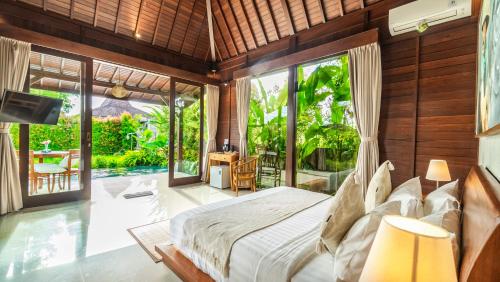 um quarto com uma cama e uma grande janela em Uma Kakul Villas em Tegalalang