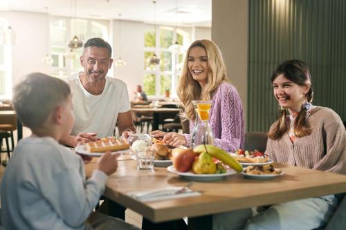 科沃布热格FACTORY RESORT wellness & spa的坐在餐桌旁吃食物的家庭