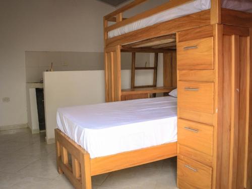 a bedroom with a wooden bunk bed with white sheets at CABAÑA VALLE REAL STAR in Turbo