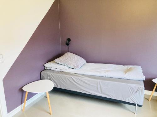 a small bed in a room with a purple wall at Villa med private værelser delt badeværelse/køkken, viby sj. in Viby