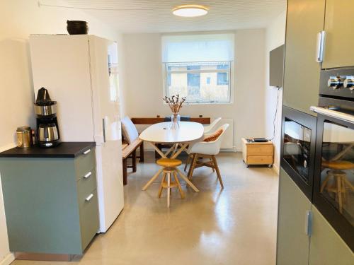 a kitchen and dining room with a table in a room at Villa med private værelser delt badeværelse/køkken, viby sj. in Viby
