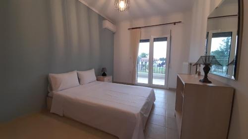 1 dormitorio con cama blanca y ventana en Villa Dimitrios(2 independent apartments 200sq m), en Vourvourou