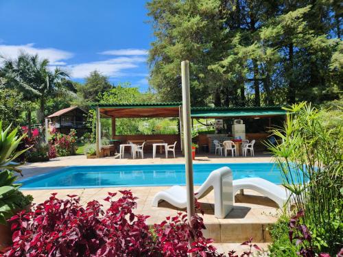 a swimming pool with a gazebo next to a house at Pousada Vale Monte Azul in Santo Antônio do Pinhal