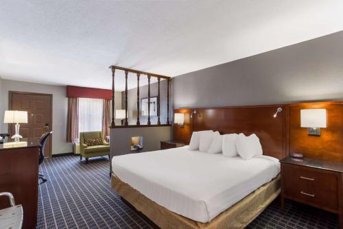 ein Hotelzimmer mit einem großen weißen Bett und einem Stuhl in der Unterkunft SureStay Plus Hotel by Best Western Greenwood in Greenwood