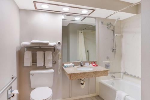 a bathroom with a toilet and a sink and a tub at SureStay Plus Hotel by Best Western Greenwood in Greenwood