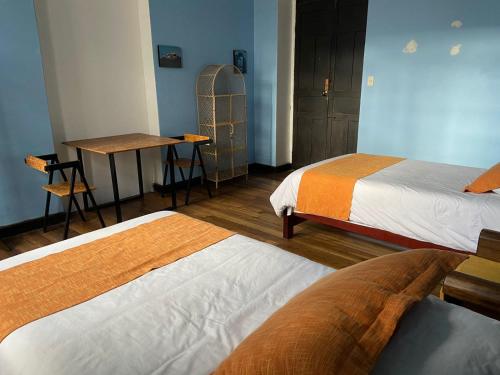a room with two beds and a table and a desk at Villa Bonita Hostel in Riobamba