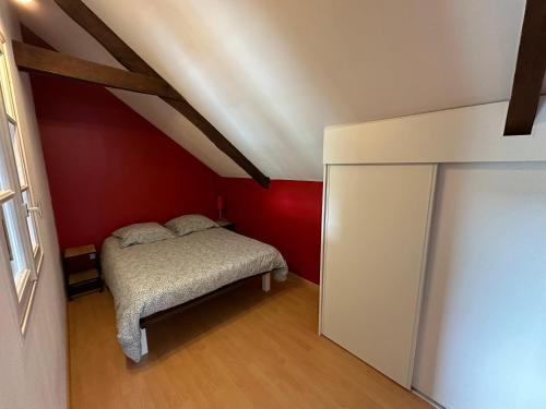 sypialnia z łóżkiem i czerwoną ścianą w obiekcie La maison du Chêne 1 w mieście Miniac-Morvan