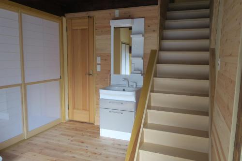 uma casa de banho com um lavatório e uma escada em Guesthouse ONE WORLD em Kitsuki
