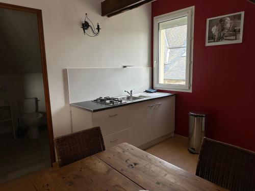 kuchnia z białą lodówką i stołem w obiekcie La maison du Chêne 1 w mieście Miniac-Morvan