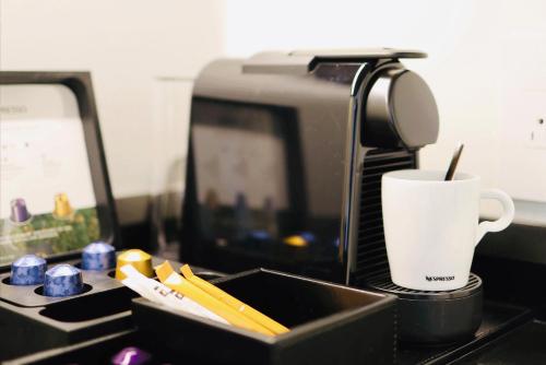 a coffee maker and a cup on a counter at AZUR Legacy Collection Hotel in Vancouver