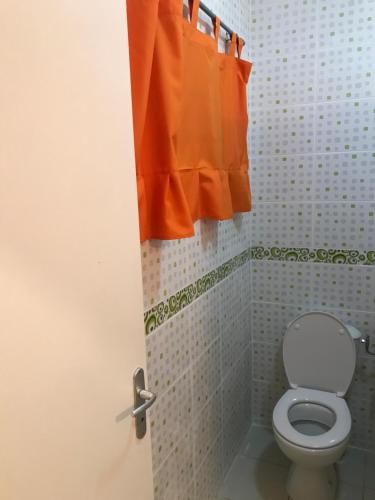 La salle de bains est pourvue de toilettes et d'un rideau orange. dans l'établissement Discrétion, à Saint-Laurent du Maroni