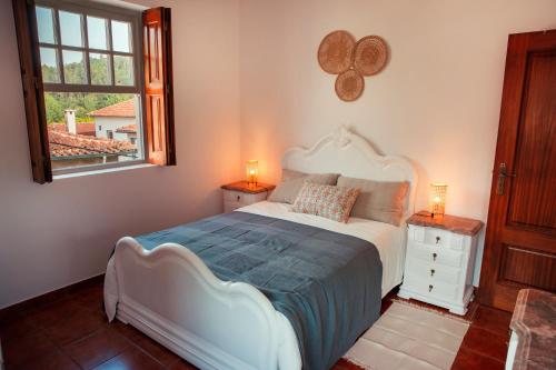a bedroom with a white bed and a window at Casa da Igreja in Ponte da Barca