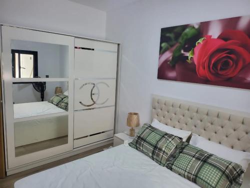 達喀爾的住宿－Appartement haut standing avec piscine，卧室配有白色的床,墙上挂着红色玫瑰