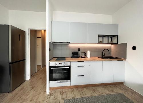 a kitchen with white cabinets and a stainless steel refrigerator at New cozy studio, private parking in Bratislava