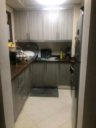 a kitchen with wooden cabinets and a black refrigerator at Moca hostel in Dubai