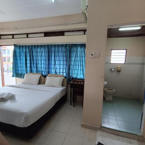 a bedroom with a bed and a desk in a room at Kota Lodge Guest House in Melaka