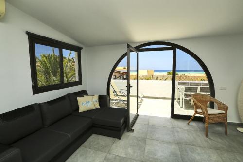 sala de estar con sofá negro y balcón en Villa Sotavento Modern new apartment in Park Natural Ocean view Adults Only, en Playa de Jandía