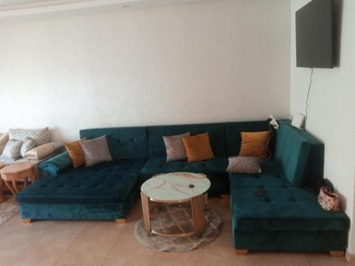 a living room with a green couch and a table at Apparemment Rockisland in Mohammedia