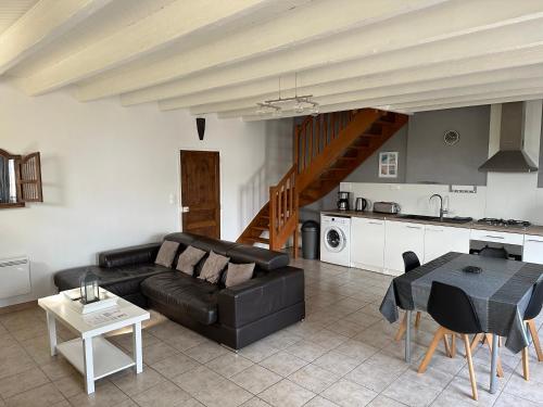 ein Wohnzimmer mit einem schwarzen Sofa und einem Tisch in der Unterkunft La maison du chêne 3 in Miniac-Morvan