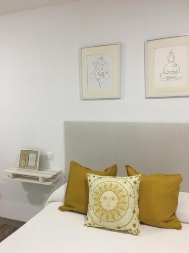 uma cama com almofadas amarelas e pinturas na parede em Estudio TAU em Jerez de los Caballeros