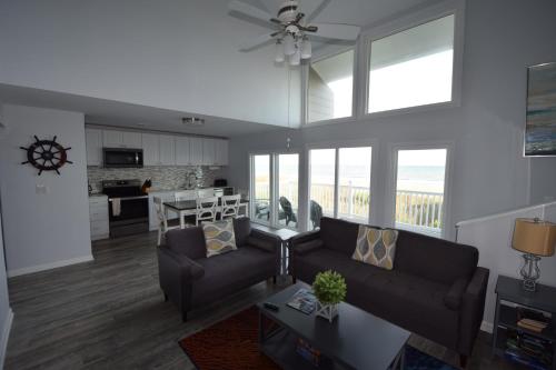 a living room with a couch and a kitchen with windows at Oceanfront vacation property - West in Emerald Isle