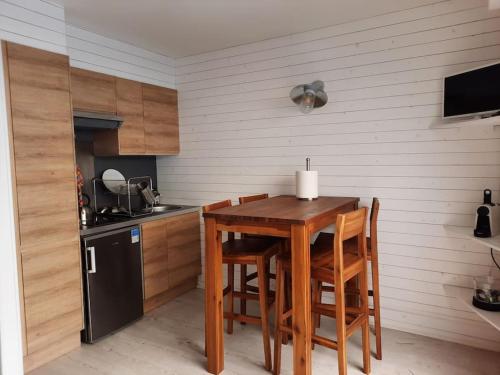 eine kleine Küche mit einem Holztisch und Stühlen in der Unterkunft Appartement terrasse, quartier très prisé in Lège-Cap-Ferret