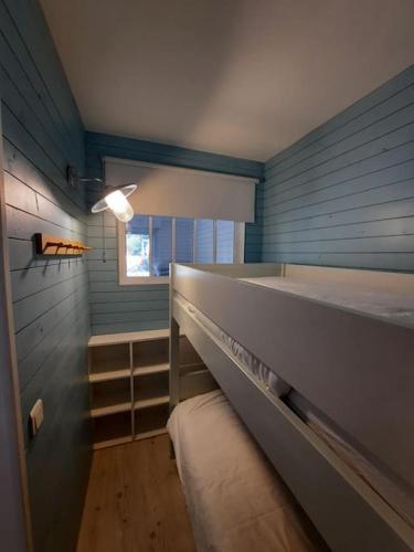 Cette chambre bleue comprend 2 lits superposés et une fenêtre. dans l'établissement Appartement terrasse, quartier très prisé, à Lège-Cap-Ferret