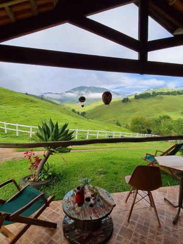 a patio with a view of a green field and balloons at Pousada Vale Monte Azul in Santo Antônio do Pinhal