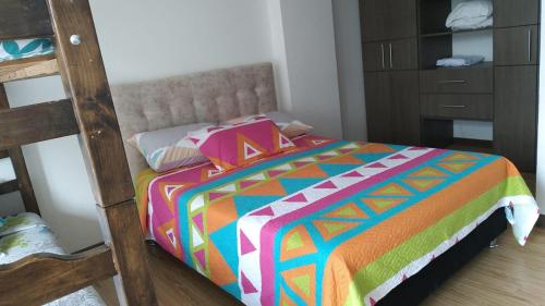 a bed with a colorful comforter in a bedroom at Apartamento Moniquira in Moniquirá