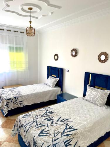 a bedroom with two beds and a chandelier at Apartamento Al Boustane-nador aljadid in Nador