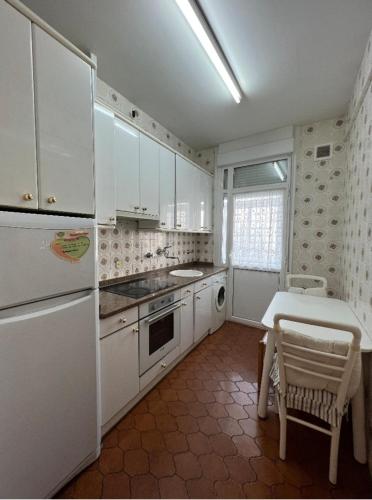 a kitchen with white cabinets and a table and a table and a stove at Apartamento Céntrico Pamplona San Fermin in Pamplona
