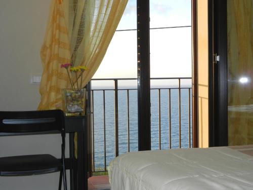 a bedroom with a view of the ocean from a balcony at FraMavi in Cefalù