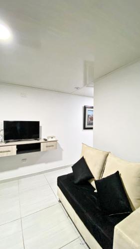 a living room with a couch and a tv on a wall at Apartahotel222 Pereira 403 in Pereira