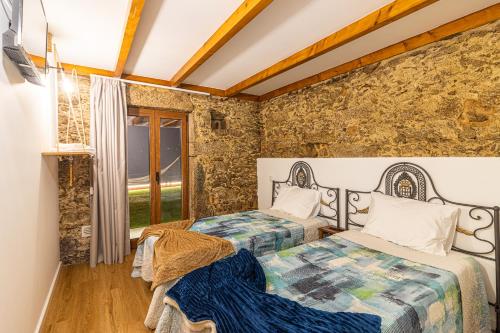 a bedroom with two beds and a stone wall at Casa Sobreiros in Sever do Vouga