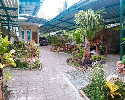 a patio with a variety of plants and trees at บ้านอังกาบ Aungkab homestay in Ban Muang Len