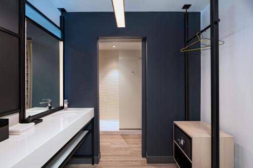 a bathroom with blue walls and a sink and a mirror at Aloft Austin Southwest in Austin