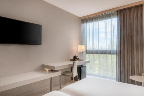 a hotel room with a bed and a desk and a window at AC Hotel San Cugat by Marriott in Sant Cugat del Vallès