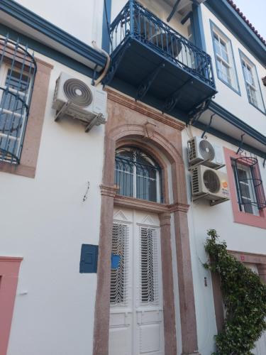 a building with a white door and a balcony at Mimosa House Ayvalık in Ayvalık