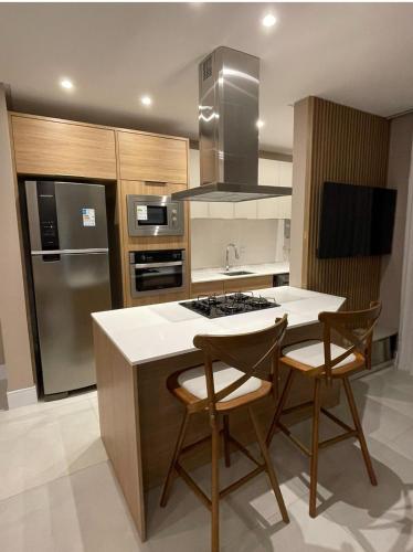 een keuken met een eiland met 2 stoelen en een fornuis bij Novinho em Camboriú in Balneário Camboriú