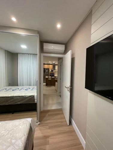 een slaapkamer met een bed en een flatscreen-tv bij Novinho em Camboriú in Balneário Camboriú