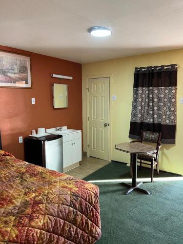 a hotel room with a bed and a table and a sink at Economy Inn Odessa in Odessa