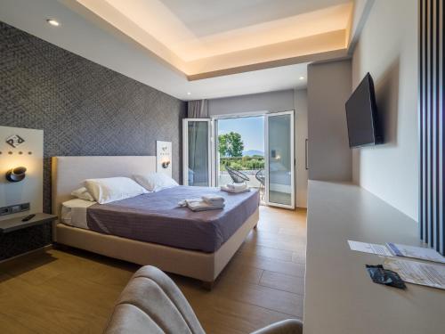 a bedroom with a bed and a tv and a balcony at Paradise Resort in Finikounta