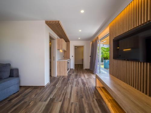 a living room with wooden floors and a tv on a wall at Paradise Resort in Finikounta