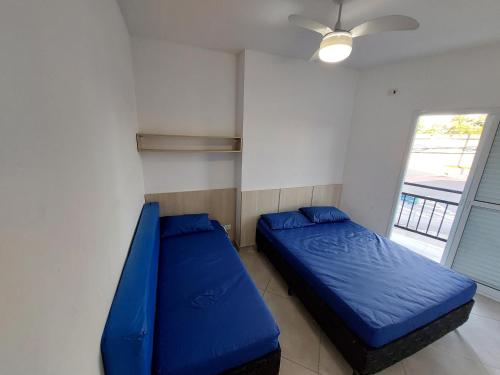 1 Schlafzimmer mit 2 blauen Betten in einem Zimmer mit Fenster in der Unterkunft Sobrado frente ao SESC, WIFI 300MB, 2 vagas auto, cozinha, churrasqueira, moderno e reformado in Bertioga
