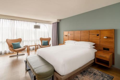 a bedroom with a large white bed and two chairs at Zurich Marriott Hotel in Zürich