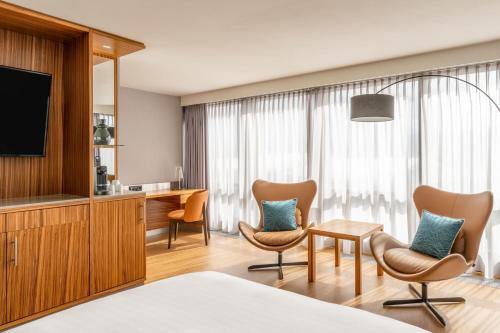 ein Hotelzimmer mit einem TV und 2 Stühlen in der Unterkunft Zurich Marriott Hotel in Zürich
