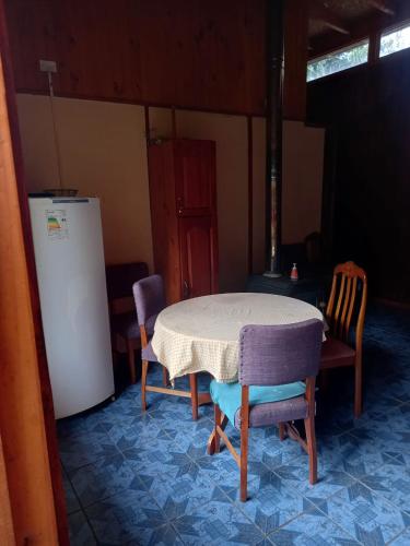 uma cozinha com uma mesa e cadeiras e um frigorífico em Cabañas Cristobal em Licán Ray