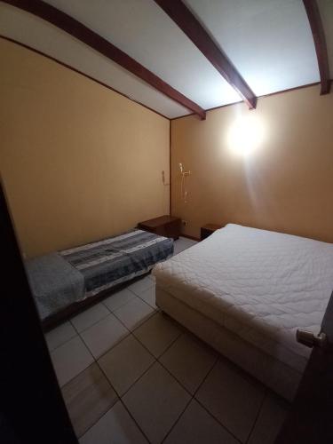 a bedroom with two beds and a light on the wall at Cabañas Cristobal in Licán Ray